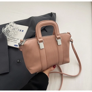Detail of pink pleated bucket bag with vertical textures and gold metal hardware