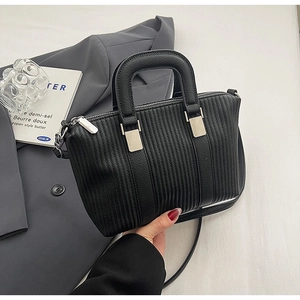 Detail of black pleated leather handbag with silver hardware and detachable strap
