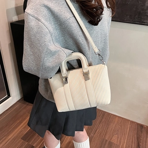 Beige textured handbag with pleated stripes and silver metal clasp for stylish daily commuting