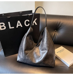 Detail of dark grey hobo tote featuring unique diagonal overlapping stitching and matte texture