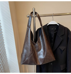 Detail of dark brown distressed leather tote bag with stitching on a metal hanger