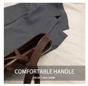 Détails d'un sac à main en cuir marron foncé avec coutures de sangle et zip doré