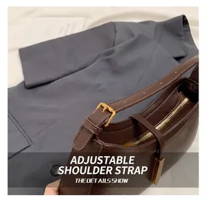 Détail de la bandoulière réglable et des ferrures dorées sur un sac à main marron foncé