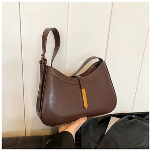 Détail d'un sac bandoulière demi-lune marron foncé avec cuir lisse et boucle en métal doré