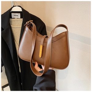 Détail d'un sac sous le bras en cuir marron avec boucle dorée et bandoulière réglable