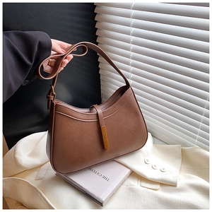 Détail d'un sac demi-lune en cuir marron avec une boucle métallique dorée élégante