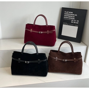 Close-up of matte suede tote bags in burgundy black and brown with decorative buckles