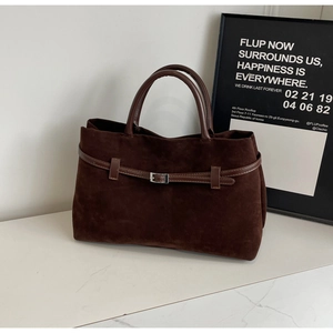 Detailed macro view of dark brown suede tote bag with leather belt and silver metal buckle