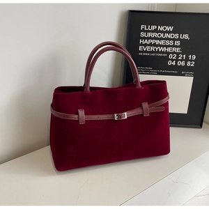 Detail of burgundy velvet tote bag featuring a leather strap and silver buckle accent