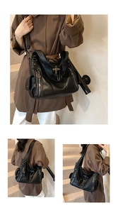 Close-up of black litchi leather tote with gothic metal cross charms and silver chain detail