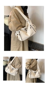 Detail of beige litchi grain tote bag with metal cross charm and side zipper pockets