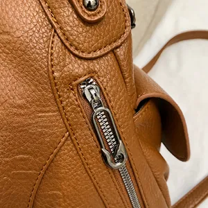 Detail of silver-grey metal zipper and litchi grain brown leather on tote bag