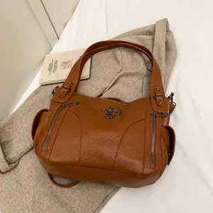 Macro detail of brown litchi leather tote with vertical zippers and metal logo