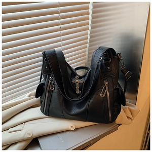 Detail of black pebbled leather tote bag with silver cross charm and clip zipper pulls
