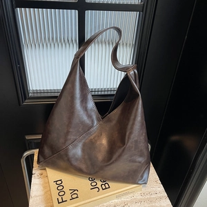 Minimalist large brown leather tote bag with vintage texture on a stone surface
