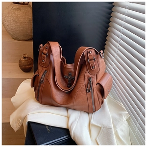 Detail of brown litchi pattern leather tote bag with vintage metal cross and pockets
