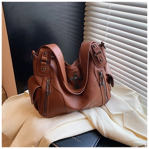 Detail of vintage brown pebble leather tote featuring a silver cross and multiple side pockets