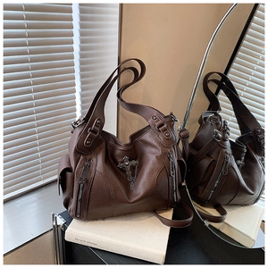 Close-up of brown litchi pattern leather tote with vintage metal cross and chain detail