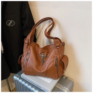 Close-up of brown pebbled leather tote with silver cross charm and side pockets