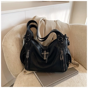 Detail of black pebbled leather tote with silver cross pendant and metal zipper accents