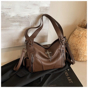 Detail of vintage brown lychee grain leather tote with silver cross pendant decoration