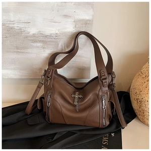 Detailed view of brown lychee leather tote with metal cross charm and vertical zippers