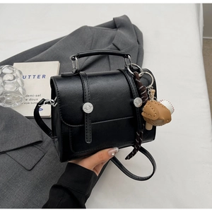 Black vintage satchel with silver buckles and a unique baseball glove bag charm