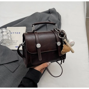 Detail of vintage brown mini satchel with decorative baseball charms and silver rivets