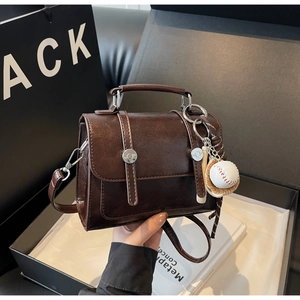 Detail of dark coffee vintage satchel with baseball charms and smooth faux leather texture