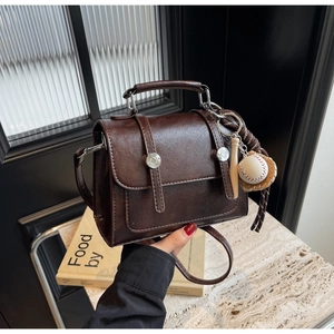 Detail shot of vintage dark brown faux leather bag with baseball charms and metal buckles