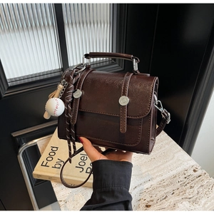 Detail of vintage brown PU leather satchel with silver buckles and baseball charm