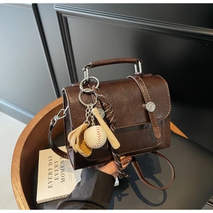 Close-up of retro brown pebbled leather bag with vintage baseball glove and bat charms