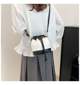 Detailed view of bicolor quilted bucket bag with golden chain and black leather straps