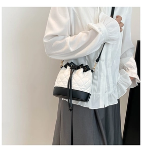 Detail of a contrast quilted drawstring bucket bag with elegant chain strap on a model