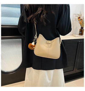 Détail d'un sac seau beige avec bordure en oreilles de chat et plaque mode sur modèle