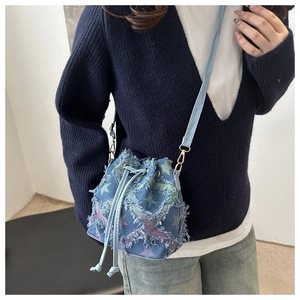 Detail of blue denim bucket bag with colorful star pattern and frayed tassel edges