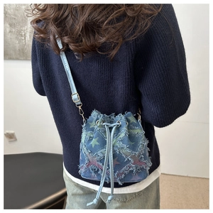 Détail du patchwork en étoile et bords effilochés sur sac seau en denim porté