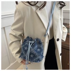 Détail du sac seau en jean bleu avec imprimé étoile, bords frangés et cordon de serrage