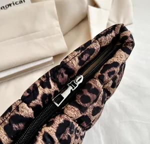 Close-up of a smooth gold metal zipper on a stylish leopard print puffer cosmetic bag