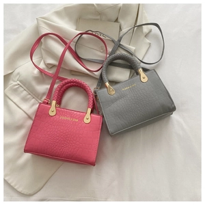 Detail of stone-patterned crossbody bags with woven handles and golden hardware