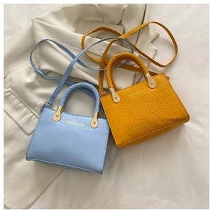 Detail view of mini crocodile texture handbags in light blue and yellow with woven handles
