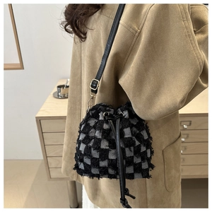 Détail du sac seau à carreaux noir et blanc avec bords effilochés et cordon de serrage