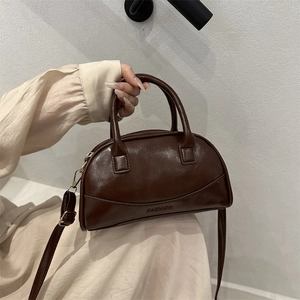 Deep brown leather shell bag with top handles and adjustable strap for crossbody wear