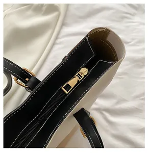 Detail of smooth gold zipper and white stitching on bicolor PU leather tote bag