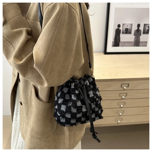 Detail of checkered bucket bag with textured fringe finish and leather drawstring strap