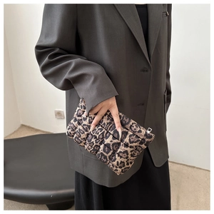 Fashionable padded leopard print clutch bag held by model wearing a grey blazer