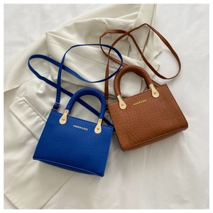 Detail of crocodile embossed crossbody bags with woven handles in blue and brown colors