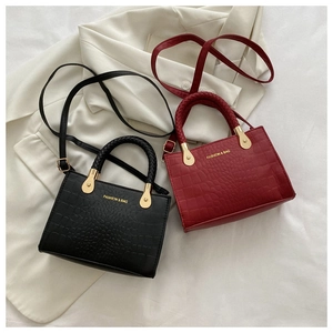 Detail showing crocodile pattern texture and braided handles on black and red bags