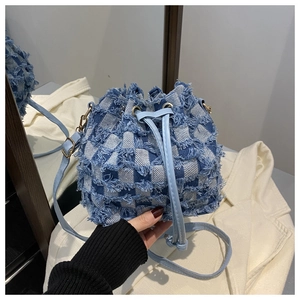 Détail du sac seau en denim à damier avec bords effilochés et fermeture à cordon