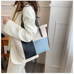 Detail of multi-color patchwork tote bag with gold metal buckle and black strap
